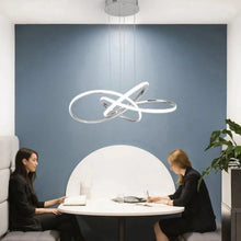 Load image into Gallery viewer, INSPIRA LIFESTYLES | Helia Twisted Pendant Light in chrome, polished gold, and matte black finishes, featuring a sculptural ribbon-like design, suspended with near-invisible wires to create a floating effect, perfect for modern interiors, dining rooms, stairwells, and contemporary living spaces, stylish lighting fixture, luxury pendant light, ambient illumination, contemporary ceiling lighting. Modern Chandelier, Minimalist Chandelier, Sculptural light, Dining table light, Living room light, LED Pendant