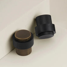 Load image into Gallery viewer, INSPIRA LIFESTYLES - Knurled Floor Door Stops featuring a crisscross diamond knurled pattern and protective rubber bumpers in Matte Black, Satin Brass and Antique Bronze.