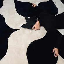 Load image into Gallery viewer, INSPIRA LIFESTYLES – Monarc Area Rug, black and ivory geometric rug, 100% polyester rug, soft and durable area rug, modern patterned rug, abstract design rug, contemporary interior rug, high-performance rug, easy-clean rug, living room rug, dining room rug, designer rug décor. Modern living room with a black and white patterned rug, wooden bench, and large windows.