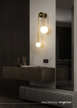Load image into Gallery viewer, INSPIRA LIFESTYLES - Gentry Wall Sconce, postmodern dual globe wall light, frosted glass wall sconce, contemporary bedside wall lighting, sculptural architectural wall lamp, luxury modern wall light in brass finish
