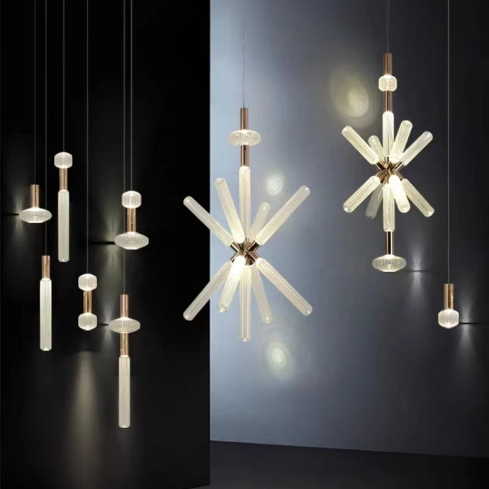 INSPIRA LIFESTYLES | Asterisk Light Sculptural glass pendant light with striped pattern from the Asterisk Light Series, cluster of tubular glass pendants forming a chandelier over stairwell, single striped glass pendant light styled beside bed, modern glass table lamp with striped detailing from the Asterisk Series, floor lamp with sculptural glass shade and minimalist base, high ceiling lighting installation featuring Asterisk pendant cluster, close-up of striped glass tubing on contemporary pendant light.