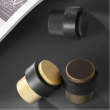 Load image into Gallery viewer, INSPIRA LIFESTYLES - Knurled Floor Door Stops featuring a crisscross diamond knurled pattern and protective rubber bumpers in Matte Black, Satin Brass and Antique Bronze.

