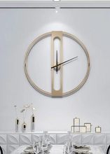 Load image into Gallery viewer, INSPIRA LIFESTYLES - Xavier Wall Clock, extra large wall clock, modern iron wall clock, sculptural wall decor, gold wall clock, charcoal wall clock, minimalist timepiece, statement wall accent, living room clock, office wall clock, oversized modern clock Modern wall clock on a white wall above a dining table with decorative items.
