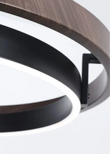 Load image into Gallery viewer, INSPIRA LIFESTYLES – Anello Duo Chandelier – sculptural two-tier chandelier with wood-patterned ring and matte black ring. Modern LED light fixture for dining rooms, living rooms, stairwells, offices, and transitional interiors.
