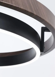 INSPIRA LIFESTYLES – Anello Duo Chandelier – sculptural two-tier chandelier with wood-patterned ring and matte black ring. Modern LED light fixture for dining rooms, living rooms, stairwells, offices, and transitional interiors.