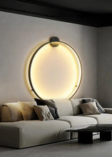 Load image into Gallery viewer, INSPIRA LIFESTYLES – Minimalist Metal Ring Light, a modern circular LED wall light with sleek sculptural design. This versatile wall sconce doubles as accent lighting and wall art, perfect as a bedroom light above a headboard, a living room statement piece, or a minimalist hallway fixture. Contemporary ring light crafted in metal with soft LED illumination, ideal for modern interiors seeking sculptural lighting, circle lights, or functional yet artistic wall sconces.
