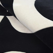 Load image into Gallery viewer, INSPIRA LIFESTYLES – Monarc Area Rug, black and ivory geometric rug, 100% polyester rug, soft and durable area rug, modern patterned rug, abstract design rug, contemporary interior rug, high-performance rug, easy-clean rug, living room rug, dining room rug, designer rug décor. Modern living room with a black and white patterned rug, wooden bench, and large windows.
