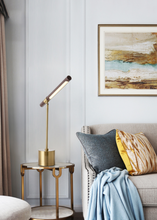 Load image into Gallery viewer, INSPIRA LIFESTYLES – Postaro Table Lamp – modern LED table lamp with postmodern design, featuring a dark wood base and satin brass accents. Sculptural yet functional lighting with a 90-degree adjustable tilt, perfect for bedside tables, home offices, and contemporary workspaces.
