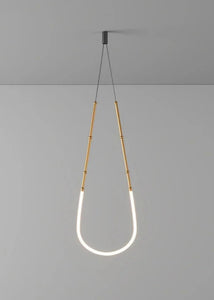 Siliq Sculptural Light with handcrafted silicone forms and metallic segmented cables, single minimalist pendant with glowing silicone tube, dramatic chandelier version of Siliq Light for high ceilings, floor-to-ceiling sculptural lighting installation in modern interior, flexible silicone light tubes emitting soft ambient glow, artistic designer light fixture styled in dining room, contemporary sculptural lighting as statement piece in commercial space.