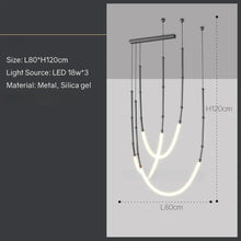 Load image into Gallery viewer, Siliq Sculptural Light with handcrafted silicone forms and metallic segmented cables, single minimalist pendant with glowing silicone tube, dramatic chandelier version of Siliq Light for high ceilings, floor-to-ceiling sculptural lighting installation in modern interior, flexible silicone light tubes emitting soft ambient glow, artistic designer light fixture styled in dining room, contemporary sculptural lighting as statement piece in commercial space.
