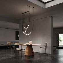 Load image into Gallery viewer, Siliq Sculptural Light with handcrafted silicone forms and metallic segmented cables, single minimalist pendant with glowing silicone tube, dramatic chandelier version of Siliq Light for high ceilings, floor-to-ceiling sculptural lighting installation in modern interior, flexible silicone light tubes emitting soft ambient glow, artistic designer light fixture styled in dining room, contemporary sculptural lighting as statement piece in commercial space.
