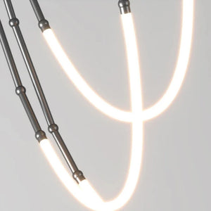 Siliq Sculptural Light with handcrafted silicone forms and metallic segmented cables, single minimalist pendant with glowing silicone tube, dramatic chandelier version of Siliq Light for high ceilings, floor-to-ceiling sculptural lighting installation in modern interior, flexible silicone light tubes emitting soft ambient glow, artistic designer light fixture styled in dining room, contemporary sculptural lighting as statement piece in commercial space.