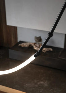 Siliq Sculptural Light with handcrafted silicone forms and metallic segmented cables, single minimalist pendant with glowing silicone tube, dramatic chandelier version of Siliq Light for high ceilings, floor-to-ceiling sculptural lighting installation in modern interior, flexible silicone light tubes emitting soft ambient glow, artistic designer light fixture styled in dining room, contemporary sculptural lighting as statement piece in commercial space.