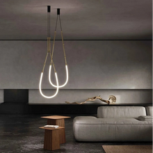 Load image into Gallery viewer, Siliq Sculptural Light with handcrafted silicone forms and metallic segmented cables, single minimalist pendant with glowing silicone tube, dramatic chandelier version of Siliq Light for high ceilings, floor-to-ceiling sculptural lighting installation in modern interior, flexible silicone light tubes emitting soft ambient glow, artistic designer light fixture styled in dining room, contemporary sculptural lighting as statement piece in commercial space.
