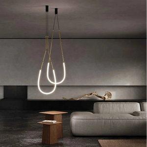 Siliq Sculptural Light with handcrafted silicone forms and metallic segmented cables, single minimalist pendant with glowing silicone tube, dramatic chandelier version of Siliq Light for high ceilings, floor-to-ceiling sculptural lighting installation in modern interior, flexible silicone light tubes emitting soft ambient glow, artistic designer light fixture styled in dining room, contemporary sculptural lighting as statement piece in commercial space.