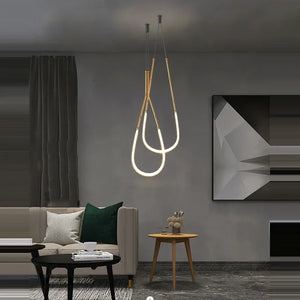 Siliq Sculptural Light with handcrafted silicone forms and metallic segmented cables, single minimalist pendant with glowing silicone tube, dramatic chandelier version of Siliq Light for high ceilings, floor-to-ceiling sculptural lighting installation in modern interior, flexible silicone light tubes emitting soft ambient glow, artistic designer light fixture styled in dining room, contemporary sculptural lighting as statement piece in commercial spaceModern living room with a stylish pendant light fixture.