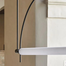 Load image into Gallery viewer, Solari Arc Light with brass arc and linear LED tube, sculptural pendant available in gold or black finish, pair of Solari Arc Lights hanging in modern dining space, minimalist arc pendant styled in office interior, contemporary pendant lighting with sleek LED tube, statement arc light fixture for high ceiling interiors. Modern outdoor light fixture on a house exterior
