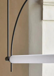 Solari Arc Light with brass arc and linear LED tube, sculptural pendant available in gold or black finish, pair of Solari Arc Lights hanging in modern dining space, minimalist arc pendant styled in office interior, contemporary pendant lighting with sleek LED tube, statement arc light fixture for high ceiling interiors. Close-up of a white door handle on a door with a neutral background