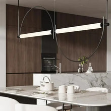 Load image into Gallery viewer, Solari Arc Light with brass arc and linear LED tube, sculptural pendant available in gold or black finish, pair of Solari Arc Lights hanging in modern dining space, minimalist arc pendant styled in office interior, contemporary pendant lighting with sleek LED tube, statement arc light fixture for high ceiling interiors. Modern kitchen with a pendant light fixture above a dining table.
