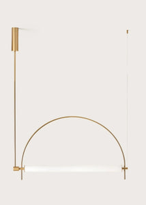 Solari Arc Light with brass arc and linear LED tube, sculptural pendant available in gold or black finish, pair of Solari Arc Lights hanging in modern dining space, minimalist arc pendant styled in office interior, contemporary pendant lighting with sleek LED tube, statement arc light fixture for high ceiling interiors. Modern gold wall-mounted light fixture on a white background