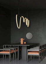 Load image into Gallery viewer, INSPIRA LIFESTYLES | Linear Rope Chandelier - Modern dining area with a black table and chairs against a dark wall, featuring a unique pendant light.
