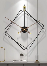 Load image into Gallery viewer, Oversized Thierry Wall Clock with minimalist iron frame and wooden arms, sculptural geometric wall clock as statement decor, modern wall clock styled in living room, large decorative wall clock in entryway, close-up of wooden hands on Thierry Wall Clock, contemporary geometric clock on neutral wall. Modern wall clock with black frame and gold accents on a white wall.
