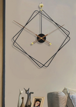 Load image into Gallery viewer, Oversized Thierry Wall Clock with minimalist iron frame and wooden arms, sculptural geometric wall clock as statement decor, modern wall clock styled in living room, large decorative wall clock in entryway, close-up of wooden hands on Thierry Wall Clock, contemporary geometric clock on neutral wall. Modern wall clock with black and gold design on a neutral wall.
